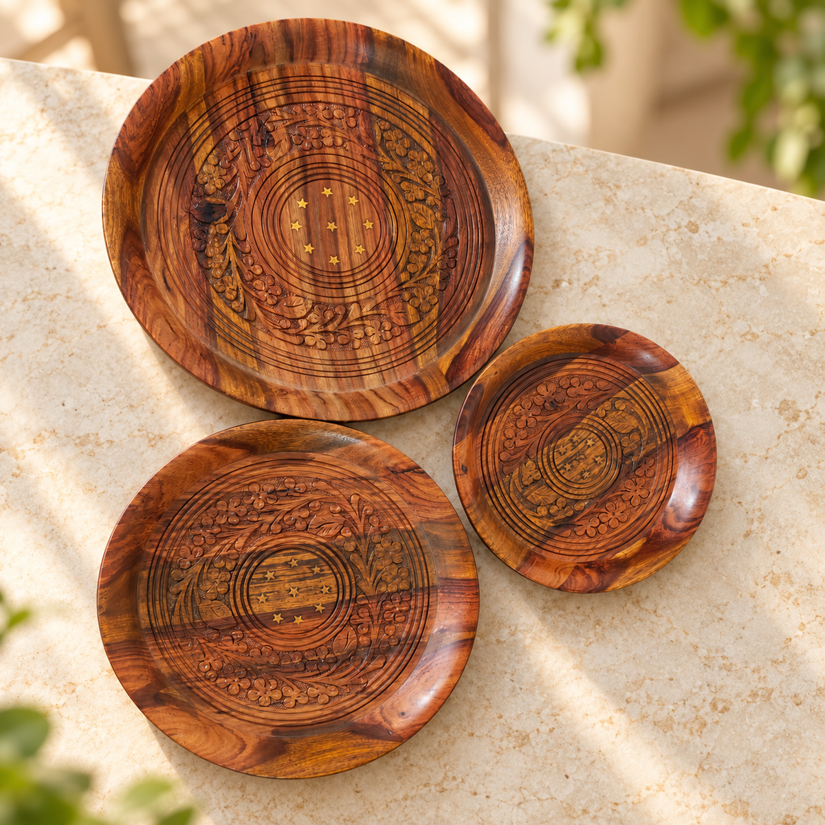 Three carved wooden plates in large, medium and small sizes on ivory tabletop
